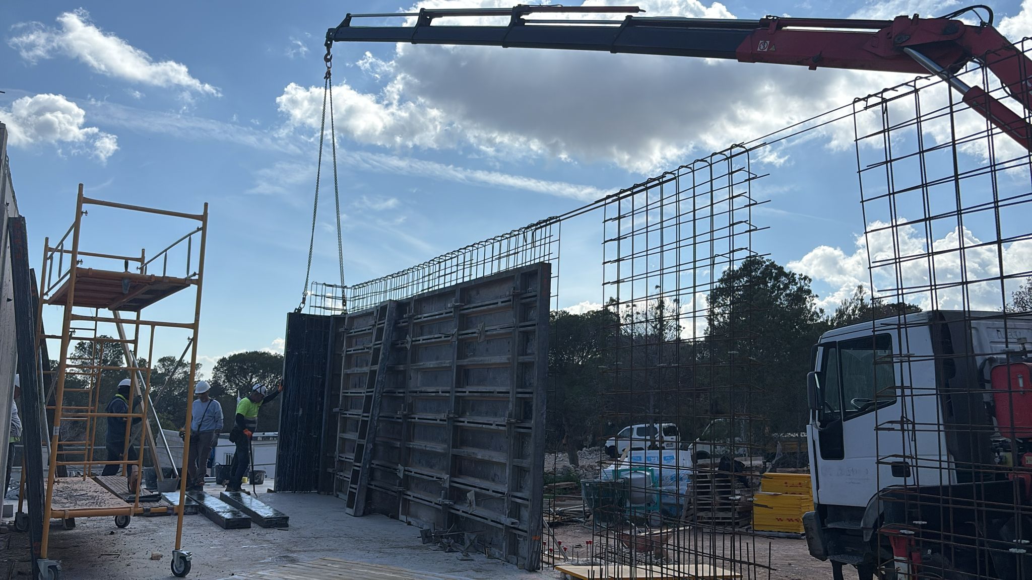 Camión grúa propio de Martínmariné Construye izando un panel de encofrado