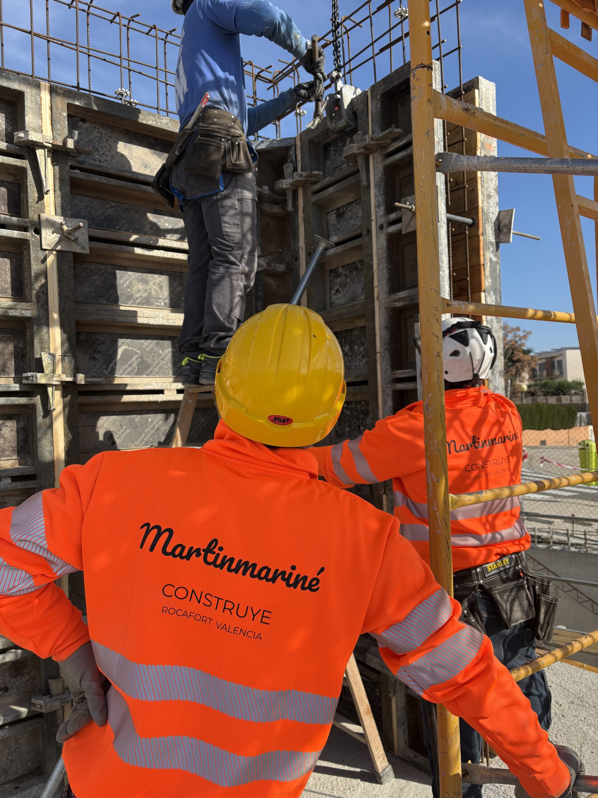 Equipo de Martínmariné Construye con chalecos de la marca montando el encofrado de un muro